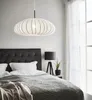 A bedroom scene with a bed, a pendant lamp, and a bedside table with a lamp and plant. Podgląd zdjęcia produktu