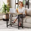 A woman is sitting on a couch next to a small rolling desk with a laptop on it. Anteprima dell’immagine prodotto