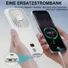 A person is holding a white portable fan and a smartphone. The phone screen shows it is charging. Produktbild-Vorschau