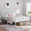 A white metal bed frame with bedding in a bedroom setting. Podgląd zdjęcia produktu