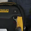 A close-up of a black and yellow Stanley FatMax tool bag with a set of keys hanging from a loop. Voir les images du produit