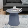 A round gray-blue side table with a magazine and a white mug on top, placed on a patterned rug in front of a gray sofa. Podgląd zdjęcia produktu