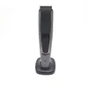 A gray electric beard trimmer is standing upright on its charging base against a white background. Produktbild-Vorschau