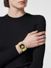 A woman wearing a black sweater is shown wearing a gold watch on her left wrist. Podgląd zdjęcia produktu