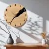 A wooden clock with a black crack design is mounted on a white wall, with shadows cast by sunlight and a nearby branch in a vase. Anteprima dell’immagine prodotto