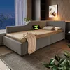 A modern bedroom with a grey upholstered daybed, a city view through the window, and decorative elements. Voir les images du produit