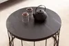 A round black coffee table with a teapot and two glasses on it, placed on a carpeted floor. Produktbild-Vorschau