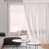 A sheer white curtain hangs in front of a large window overlooking a body of water and a rocky landscape. A sofa and ottoman are visible in the foreground. Náhľad obrázku produktu