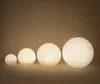 Four glowing spherical lamps of varying sizes are arranged in a line against a plain, light brown background. Produktbild-Vorschau