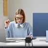 A woman is working at a desk with multiple electronic devices connected to a power strip. Produktbild-Vorschau