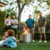 A group of people gathered around a fire pit in a backyard during the evening. Produktbild-Vorschau