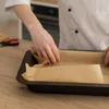 A person in a chef's coat is lining a baking tray with parchment paper. Produktbild-Vorschau