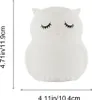 A white owl-shaped night light with closed eyes and eyelashes is shown against a white background. Dimensions are indicated by lines and text. Produktbild-Vorschau