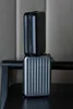 Two small, rectangular cases are stacked on top of each other on a dark surface, with a textured background behind them. Anteprima dell’immagine prodotto