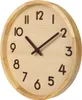 A close-up view of a wooden wall clock with dark brown hands and numbers. Produktbild-Vorschau