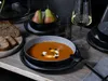 A table setting with a bowl of soup, bread, pears, and a glass of white wine. Náhľad obrázku produktu