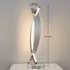 A modern LED table lamp with a silver finish, shown on a white surface against a textured light gray wall. Dimensions are indicated with measurement lines and text. Produktbild-Vorschau