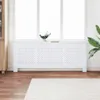A white radiator cover is placed in front of a large window. Náhled obrázku produktu