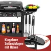 A close-up view of a black gas grill with various accessories and condiments displayed, along with a plate of fruits and a call-to-action overlay. Produktbild-Vorschau