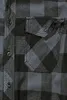 A close-up view of a black and gray plaid shirt, showing the pocket and buttons. Produktbild-Vorschau