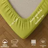 A close-up of a lime green fitted sheet corner, showing the elastic edge and some product information. Produktbild-Vorschau
