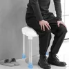 A person sitting on a white shower stool in a bathroom setting. Produktbild-Vorschau