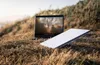 A Starlink Mini internet kit and a laptop are set up on a grassy hillside. Produktbild-Vorschau