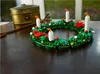 A LEGO wreath with candles and decorations sits on a wooden table, with a brass container in the background. Podgląd zdjęcia produktu