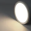 A close-up shot of a round, flat LED ceiling light mounted on a wall. Voir les images du produit