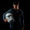 A young person holding a stormtrooper helmet against a black background. Voir les images du produit