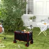A foldable wagon filled with items sits on a grassy lawn in a backyard setting, with a house and trees in the background. Produktbild-Vorschau