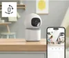 A security camera is shown on a wooden surface, with a smartphone displaying its feed in the foreground. Produktbild-Vorschau
