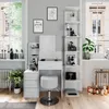 A white vanity table with a stool and shelves filled with makeup and decor, set in a bright room with large windows. Náhled obrázku produktu