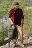 A man in outdoor clothing stands on a rocky surface with a backpack. Anteprima dell’immagine prodotto
