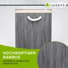 A close-up marketing image of a grey bamboo laundry basket with a rope handle and a beige rim, set against a light gray and white background. A circular inset shows a close-up of the bamboo texture. Text overlays highlight the product's material and aesthe Náhľad obrázku produktu