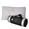 A white pillow is shown next to its rolled-up packaging, which is black with gold and white text. Produktbild-Vorschau