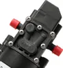 A close-up view of a black diaphragm pump with red caps on two of its fittings. Podgląd zdjęcia produktu