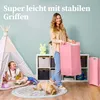A woman is holding a pink laundry basket in a child's room with a teepee, toys, and a dog. Anteprima dell’immagine prodotto