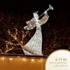 A lighted angel decoration with a trumpet, set against a dark background with fairy lights. Náhled obrázku produktu
