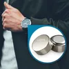 A person wearing a watch is shown next to a close-up of button cell batteries. Produktbild-Vorschau
