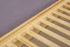 A close-up view of a wooden bed frame with slats and a grey mattress. Produktbild-Vorschau