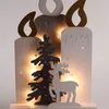 A wooden Christmas decoration featuring three candle shapes, a Christmas tree, and a reindeer, illuminated by warm LED lights. Produktbild-Vorschau