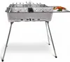 A stainless steel barbecue grill with folding legs, skewers, and a small rack of vegetables on the side. Produktbild-Vorschau