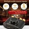 A close-up of a black audio amplifier with gold knobs, set against a blurred background of a theater or concert hall. Produktbild-Vorschau