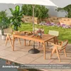 An outdoor dining set with a wooden table and chairs, set on a patio next to a pool, with plants and flowers in the background. Náhled obrázku produktu