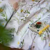 A close-up view of a bed with floral patterned bedding, a book, and a cup of tea. Produktbild-Vorschau