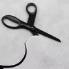 A pair of black scissors is shown cutting a piece of white fabric. Náhľad obrázku produktu