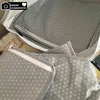 A close-up view of grey polka dot fabric with zippers, likely part of a luggage organizer set. Voir les images du produit