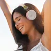 A young woman with her arms raised, wearing headphones and smiling. Produktbild-Vorschau