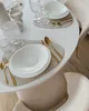 A dining table set with white plates, gold cutlery, and glassware. Podgląd zdjęcia produktu